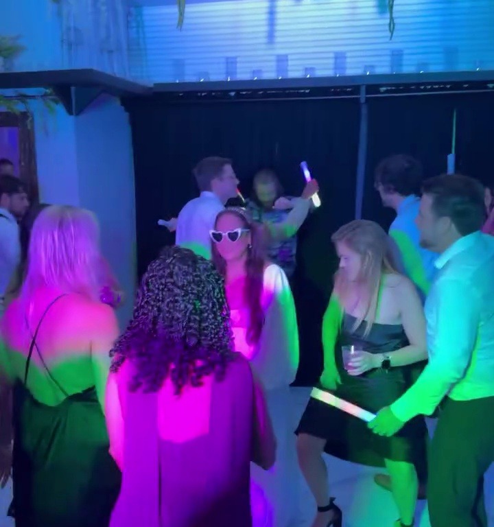 Packed dance floor with colorful lights and glow sticks at wedding reception