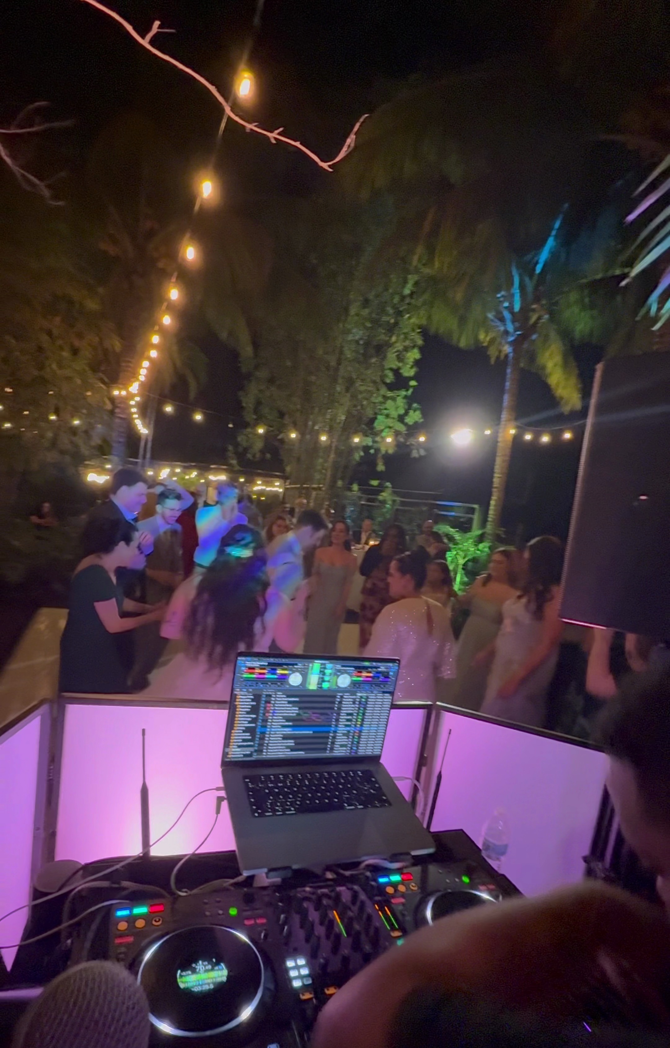 Behind the decks at outdoor wedding with string lights and crowd