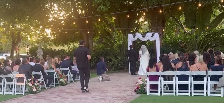 Wedding ceremony with string lights, bride and groom at altar